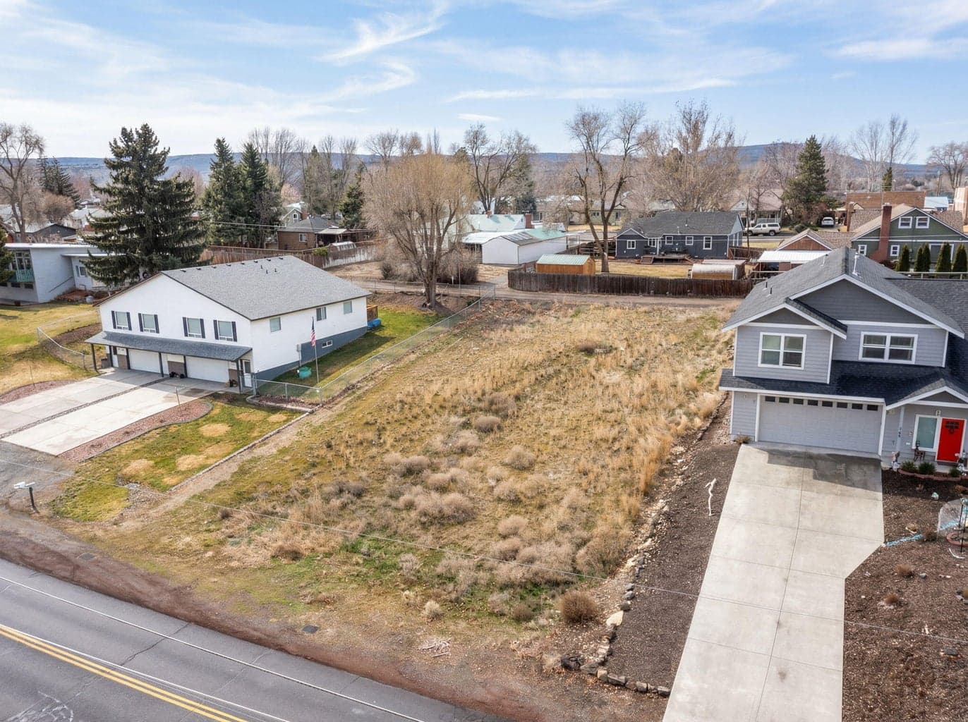 Close-up of the building site, highlighting the clear terrain and paved street access.