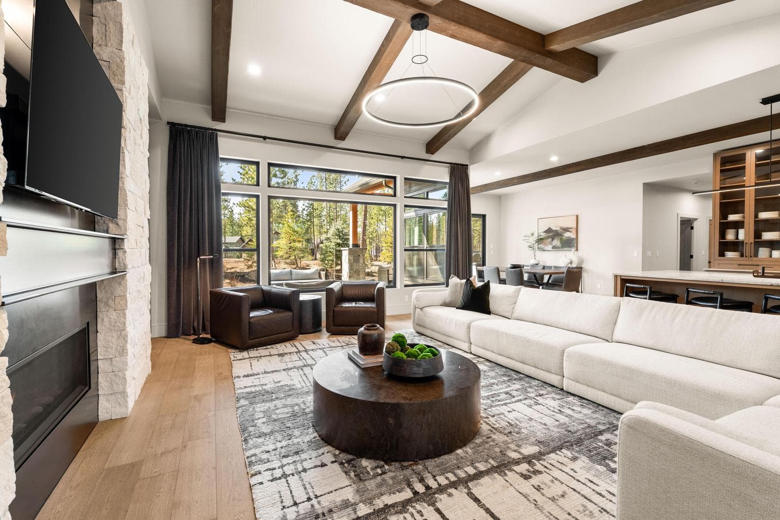 Designed with vaulted ceilings, warm wood beams, and expansive windows, the home blends rustic charm with refined modern touches.