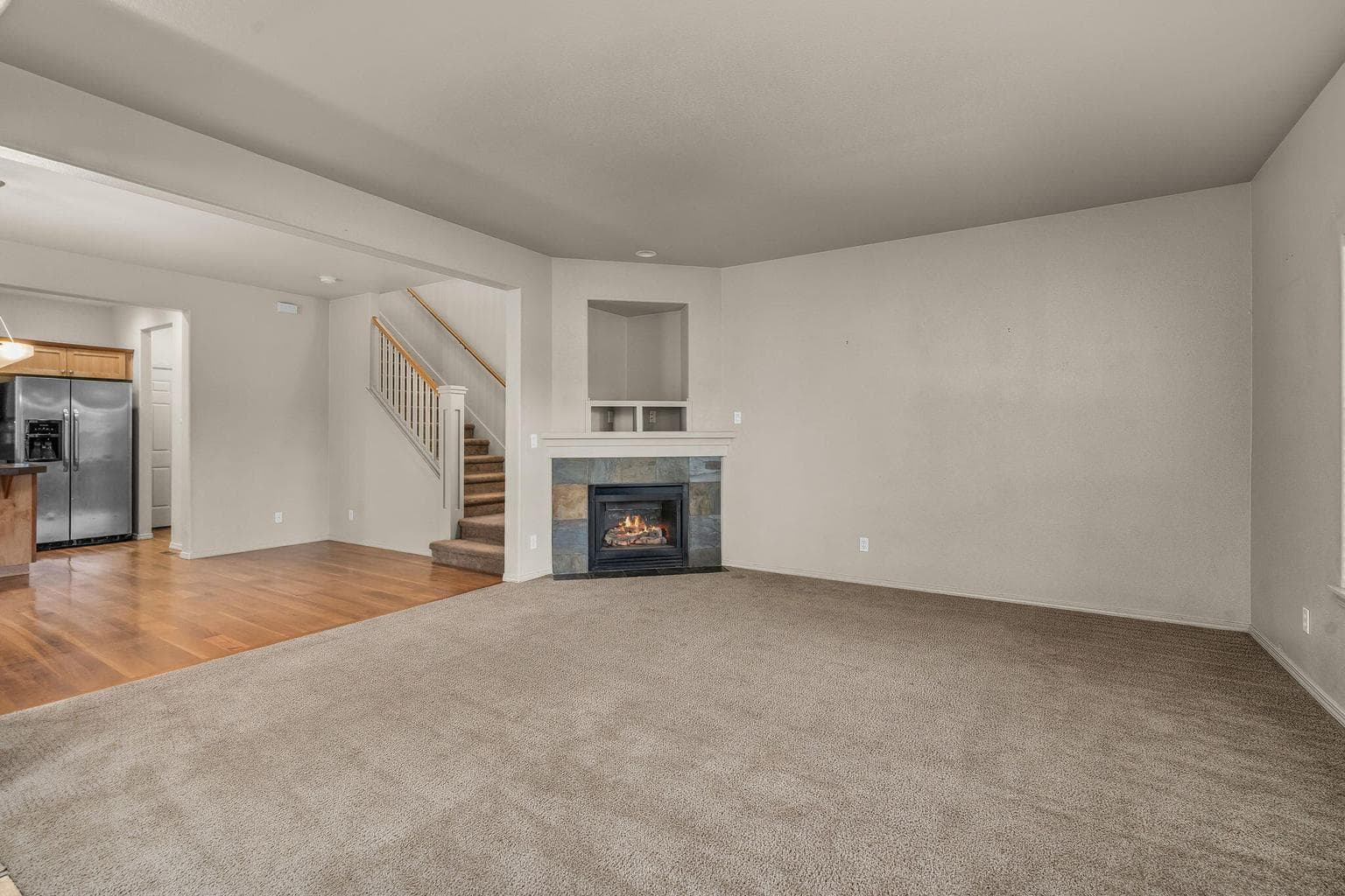 Spacious living area featuring fireplace and staircase leading to the upper level.