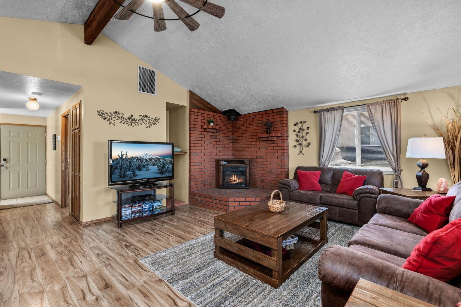 Main living area featuring vaulted ceilings, laminate flooring, and a wood-burning stove.