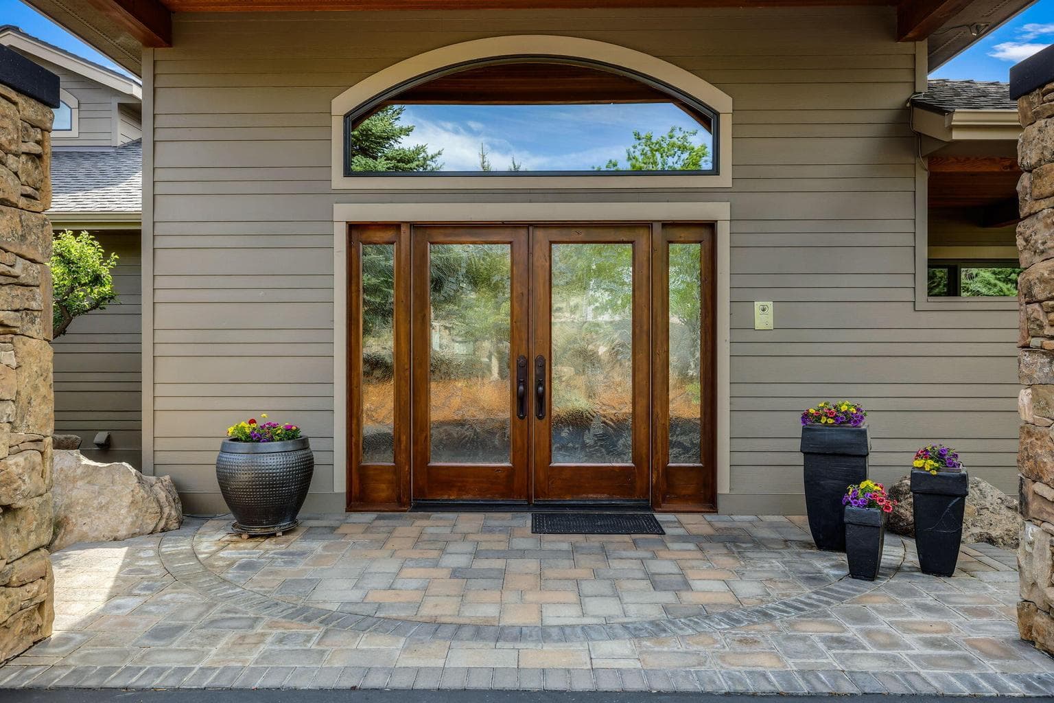 Montana Mossy Rock Pillars/Siding Features Imported Custom Rust Cuernites Sconces on Pillars, w/ Dimmer
Black Cement Trim Features -top of Pillars and Rock Wall Siding Across Front of Home
Timbered Custom Wood Arch Features
Cedar Paneled Ceiling w/ Spot lighting on Dimmer
Jamestown Blend Pavers, Park & Plaza Stone Cobble w/ Holland Stone-Grey Charcoal Border