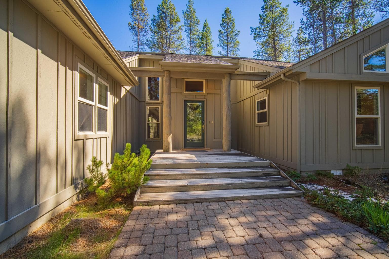 Covered front entry with paver approach, wood accents, and a welcoming Sunriver resort-home feel.