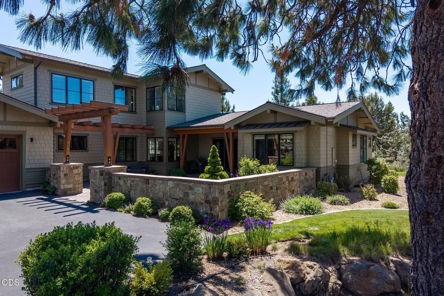 Striking Tetherow exterior with natural stone walls, timber accents, landscaped courtyard, and a private, welcoming approach.