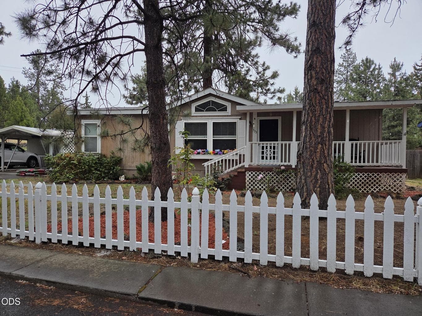 1188 sq ft, 3 bedrooms, 2 baths, 1995 manufactured home with carport and storage, and a white picked fence.